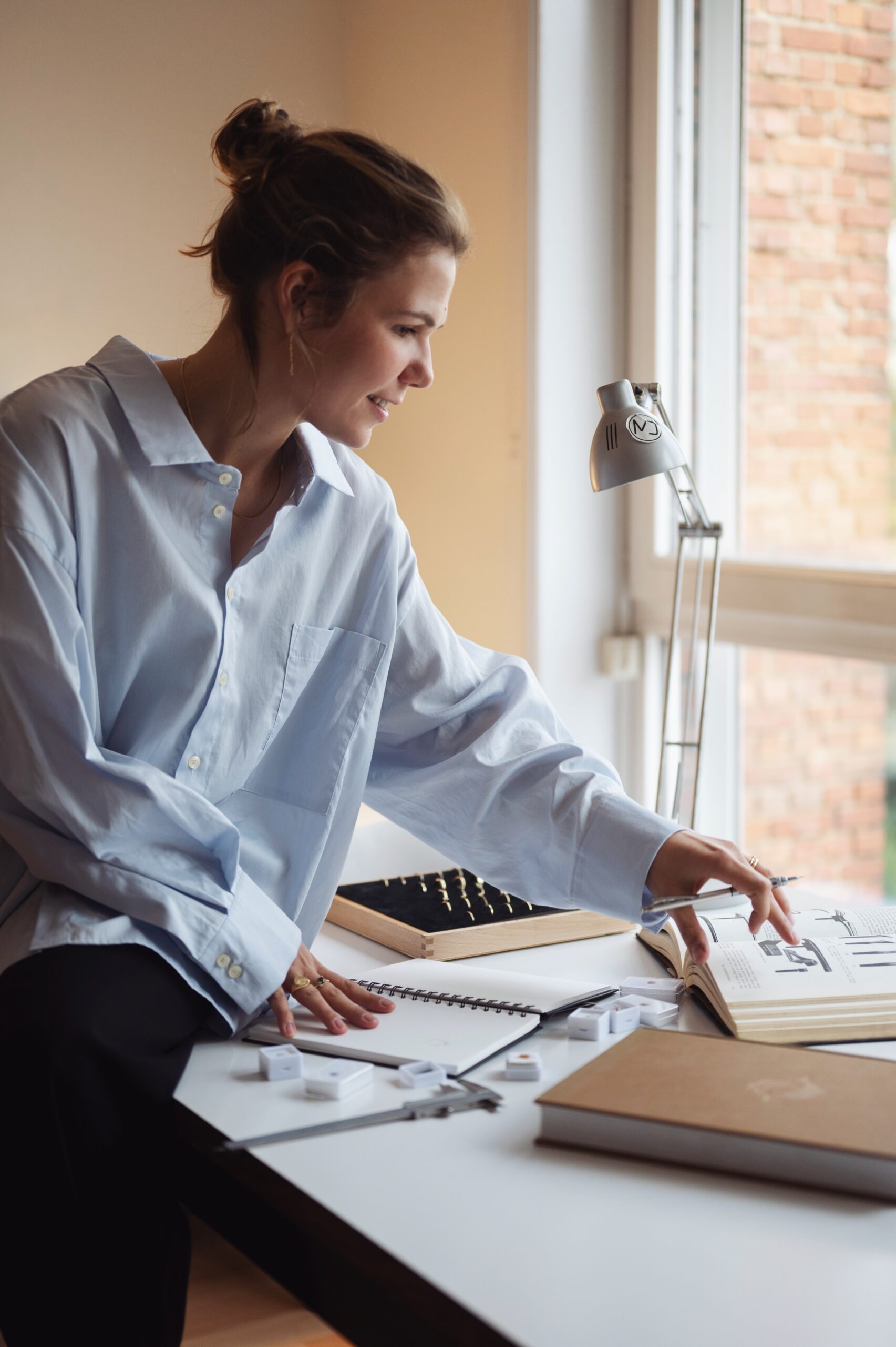 Margot leunt op een bureau en kijkt in juwelenboek